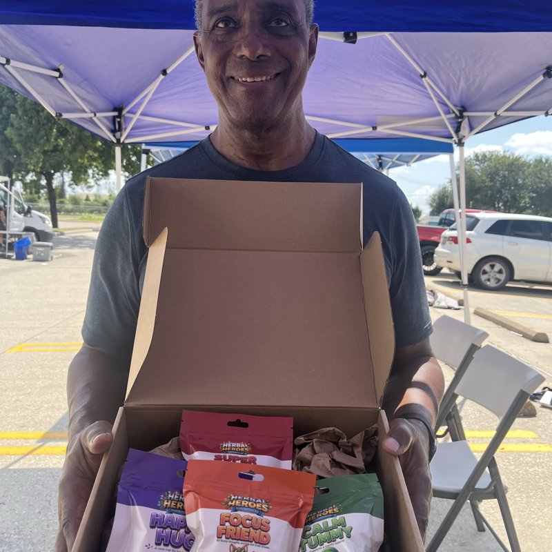 Herbal Heroes founder holding an open bundle box at the LBJ Market